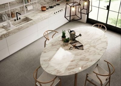 Modern kitchen with marble countertops, an oval marble dining table, wooden chairs, pendant lights, large windows, and sleek kitchen cabinets.