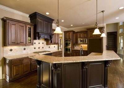 Luxurious kitchen with dark wood cabinets, granite countertops, pendant lights, stainless steel appliances, and elegant marble flooring.