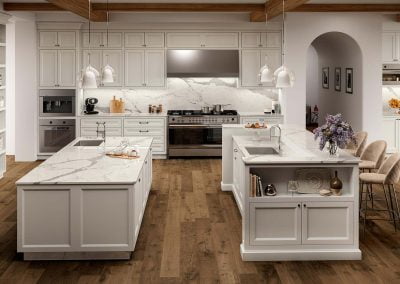 Modern kitchen with marble countertops, two islands, pendant lights, stainless steel appliances, wooden floor, and elegant kitchen cabinets.