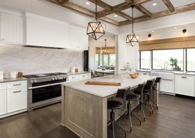 Modern kitchen with a large island, geometric pendant lights, white cabinets, quartz countertops, and stainless steel appliances.