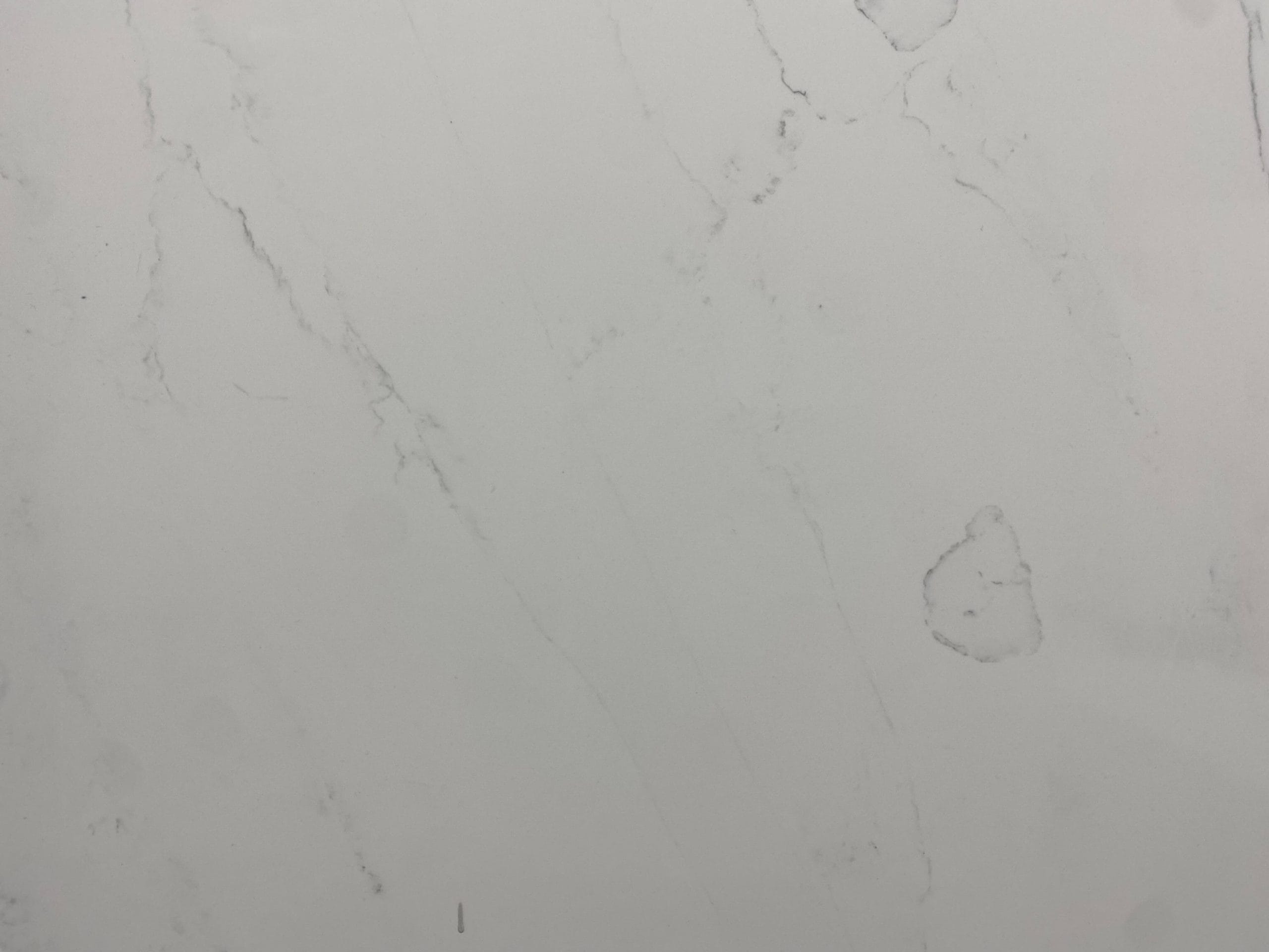 White marble surface with subtle gray veins and faint, irregular spots.