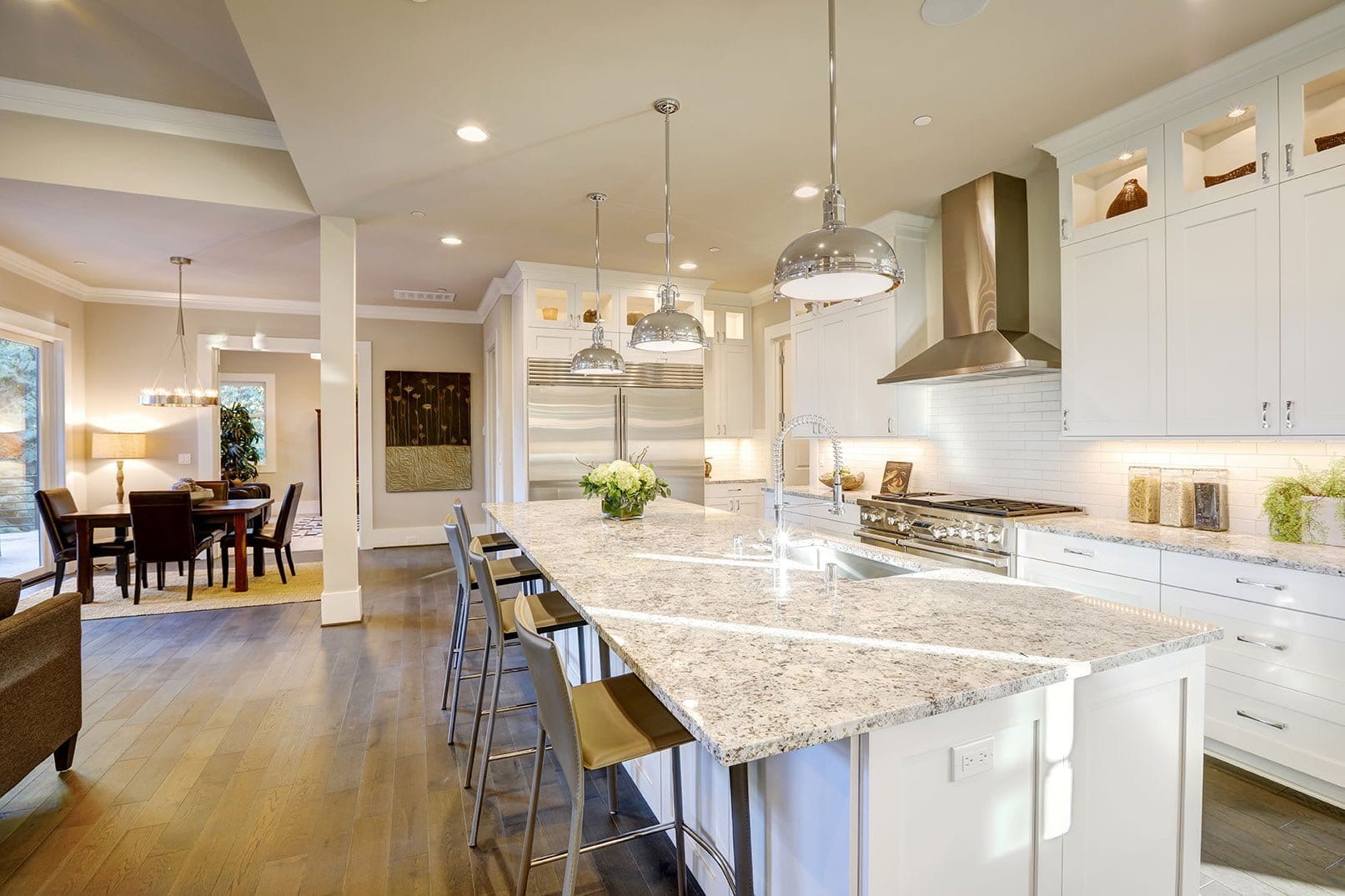 Modern kitchen with white cabinets, stainless steel appliances, and a large marble island with bar stools.